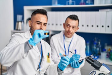 Two men scientist writing on document holding pills at laboratory