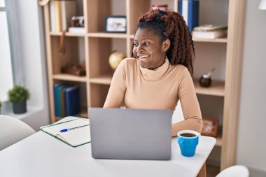African american woman student using laptop studying at home