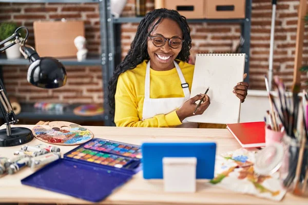 stock image African american woman artist having online paint lesson at art studio