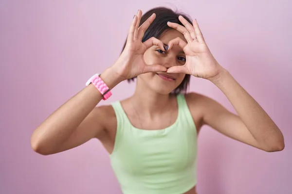 Pembe Arka Planda Duran Genç Kız Kalp Şeklinde Elleriyle Parmaklarıyla — Stok fotoğraf