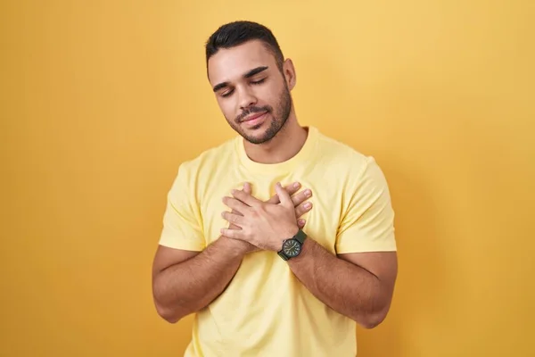 Young Hispanic Man Standing Yellow Background Smiling Hands Chest Closed — Stock fotografie
