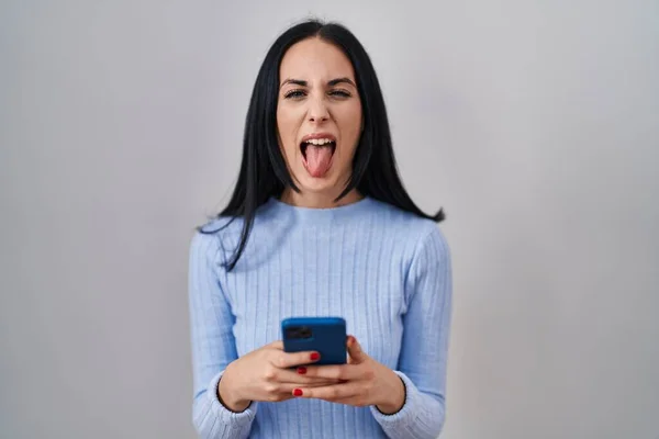 Hispanic Woman Using Smartphone Sticking Tongue Out Happy Funny Expression — Fotografia de Stock