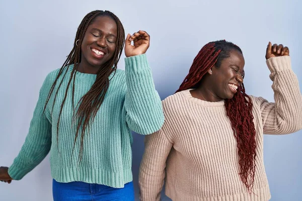 Dwie Afrykańskie Kobiety Stojące Nad Niebieskim Tle Tańczące Szczęśliwe Radosne — Zdjęcie stockowe