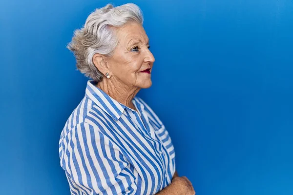 Ηλικιωμένη Γυναίκα Γκρίζα Μαλλιά Στέκεται Πάνω Από Μπλε Φόντο Κοιτάζοντας — Φωτογραφία Αρχείου