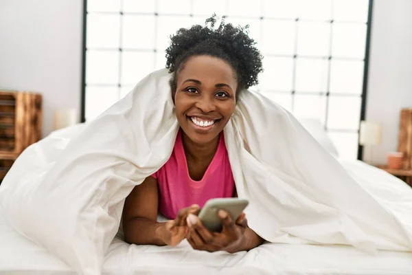 African American Woman Using Smartphone Lying Bed Bedroom — Stok fotoğraf