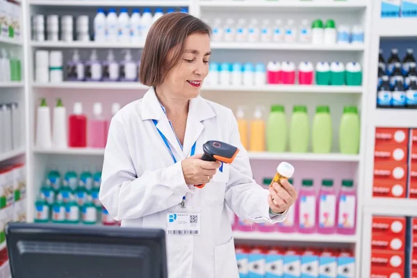 stock image Middle age woman pharmacist scanning pills bottle at pharmacy