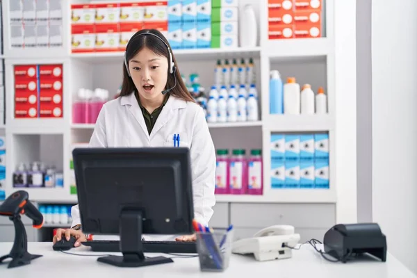 Китайская Молодая Женщина Работающая Аптеке Наушниках Испуганная Удивленная Открытым Ртом — стоковое фото
