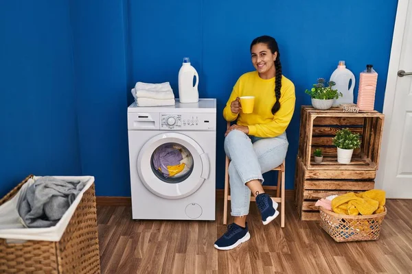 Young Hispanic Woman Drinking Coffee Waiting Washing Machine Laundry Room — Stok fotoğraf