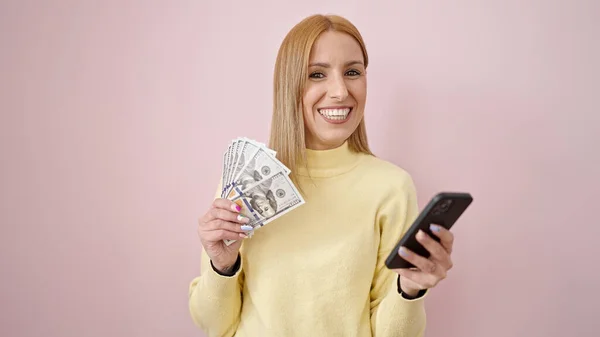 Junge Blonde Frau Benutzt Smartphone Mit Dollars Vor Isoliertem Rosa — Stockfoto
