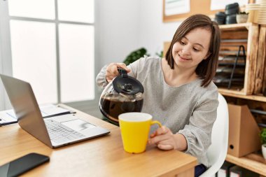 Down sendromlu esmer kadın iş yerinde bir fincan kahve içiyor.