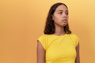 Young african american woman standing with sad expression over isolated yellow background