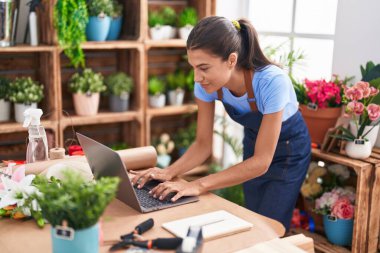 Çiçekçiye dizüstü bilgisayar kullanarak gülümseyen güzel İspanyol kadın.
