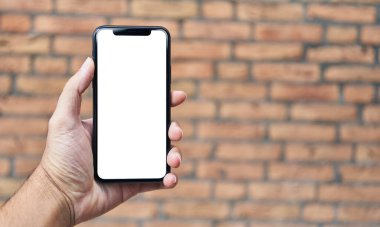 Akıllı telefonu tutan adam, izole edilmiş tuğla arka planda beyaz beyaz ekran gösteriyor