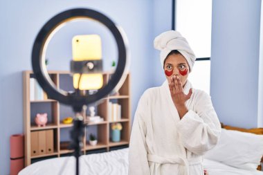 Koyu renk saçlı İspanyol kadın akıllı telefonuyla güzellik dersi kaydediyor ağzını eliyle kapatıyor, şok geçiriyor ve hata yapmaktan korkuyor. şaşırmış ifade 