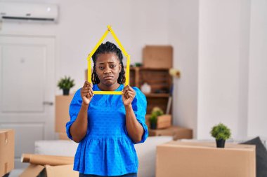 Yeni evinde örülmüş saçları olan Afrikalı bir kadın elinde cetvel tutuyordu. Depresyondaydı ve üzüntüden ağlıyordu. Kızgın ve korkmuştu. hüzünlü ifade. 