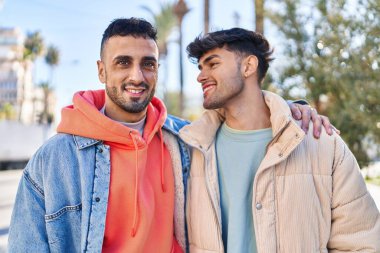 İki erkek caddede birbirlerine sarılıyorlar.