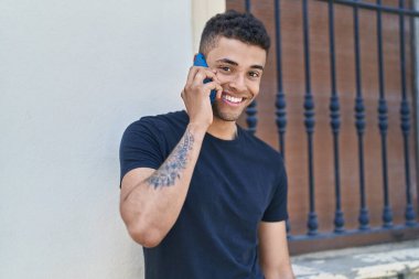 Afro-Amerikalı adam gülümsüyor. Kendine güveniyor. Akıllı telefondan konuşuyor.