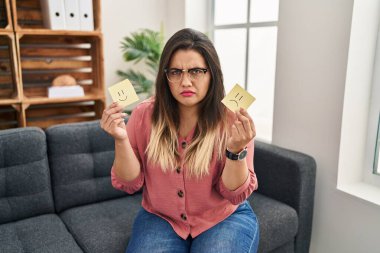 Genç İspanyol kadın, elinde mutlu duygulara karşı hüzünlü şüpheci ve gergin bir kağıt tutuyor, sorun yüzünden suratını asıyor. negatif kişi. 