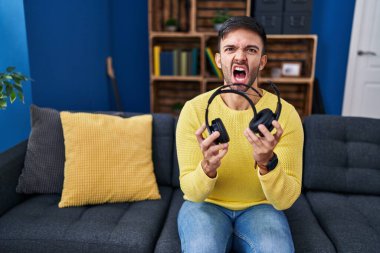 Kırık kulaklıkları olan İspanyol bir adam öfkeli ve kızgın çığlıklar atıyor öfkeyle bağırıyor. öfke ve agresif konsept. 