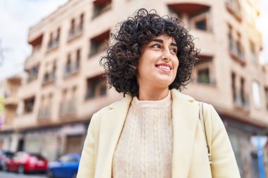 Young middle east woman excutive smiling confident looking to the side at street