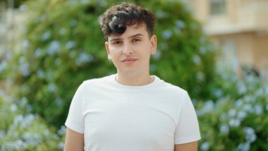 İkili olmayan adam parkta ciddi bir ifadeyle duruyor.