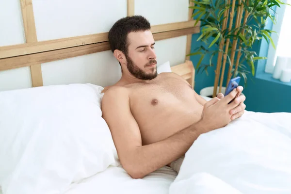 Jovem Hispânico Usando Smartphone Deitado Cama Quarto — Fotografia de Stock