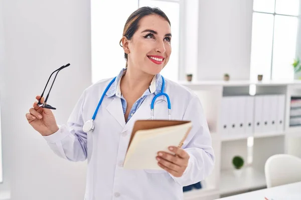 Young Beautiful Hispanic Woman Doctor Smiling Confident Reading Notebook Clinic — Stock Photo, Image