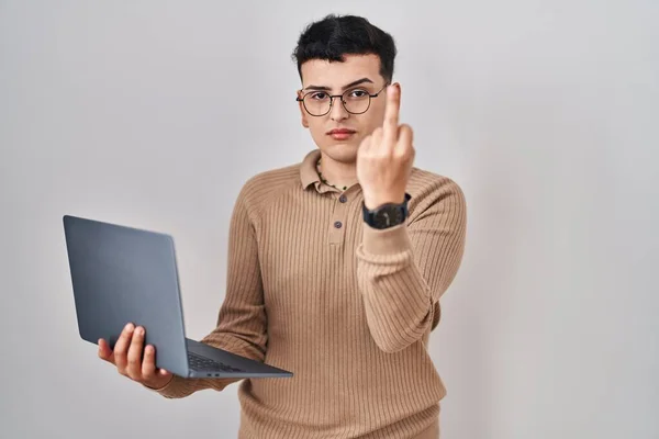 Non binary person using computer laptop showing middle finger, impolite and rude fuck off expression
