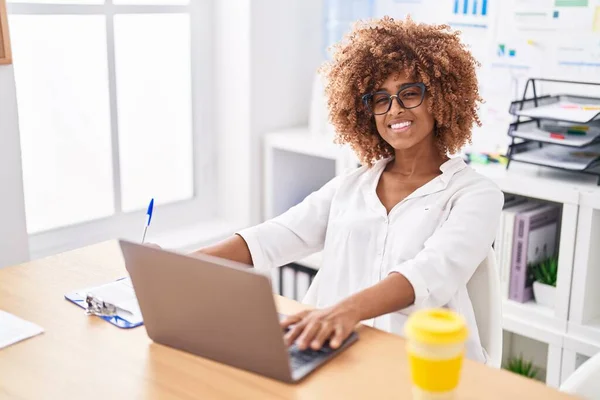 使用笔记本电脑在办公室文件上书写的非洲裔美国女商人 — 图库照片