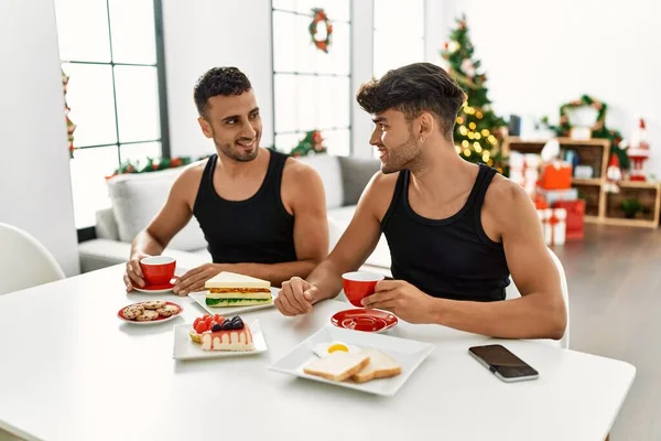 Two Hispanic Men Couple Having Breakfast Sitting Christmas Tree Home — Stock Photo, Image