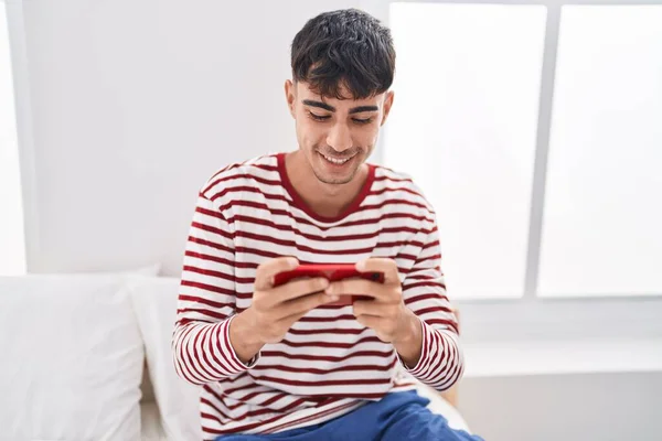 Young Hispanic Man Playing Video Game Sitting Bed Bedroom — Stok fotoğraf