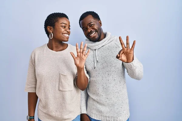 一对年轻的非洲裔美国夫妇站在蓝色的背景上 用八号手指指指指点点 面带微笑 自信而快乐 — 图库照片