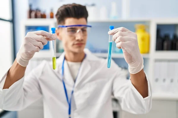stock image Young hispanic man wearing scientist uniform holding test tubes at laboratory