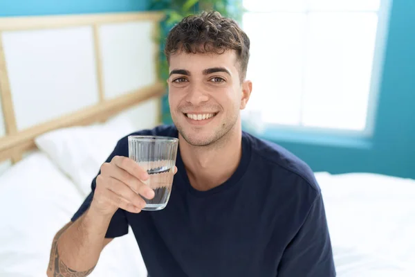 Young Hispanic Man Drinking Glass Water Sitting Bed Bedroom — Stockfoto