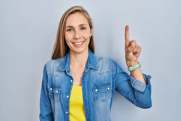 Young Blonde Woman Standing Blue Background Showing Pointing Finger Number — Φωτογραφία Αρχείου