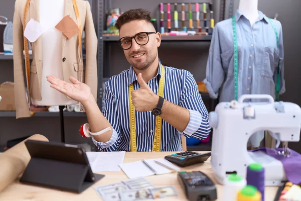 西班牙男人 胡须裁缝师设计师 在工作室工作 展示手掌 竖起大拇指做手势 面带微笑 快乐而快乐 — 图库照片