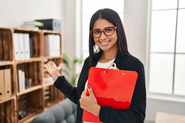 stock image Young latin woman psychologist holding clipboard standing at clinic