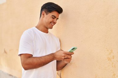 Sokakta akıllı telefon kullanan, kendine güvenen genç bir İspanyol.