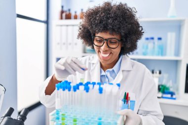 Laboratuvarda test tüpleri tutan Afrikalı Amerikalı kadın bilim adamı.