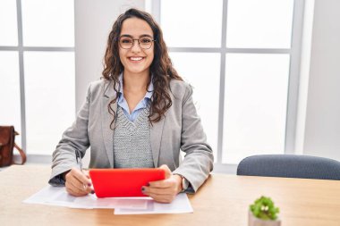 Young hispanic woman business worker using touchpad working at office