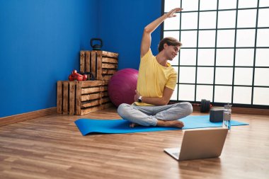 Young caucasian man smiling confident having online stretching class at sport center