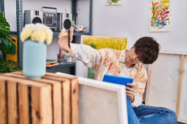 Young hispanic man artist using touchpad drawing at art studio