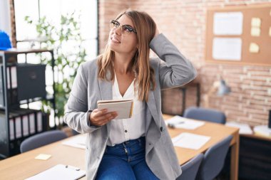 Ofiste çalışan genç İspanyol bir kadın. Gözlüklü, gülümseyen, kendine güvenen, el hareketleriyle saçlarına dokunan çekici ve modaya uygun poz veren. 