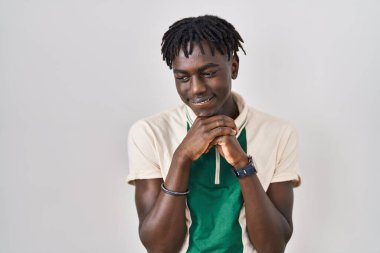 Münzevi arka planda dikilen Afrikalı adam elleri çenesinde gergin ve heyecanlı bir şekilde yan tarafa bakıyor. 