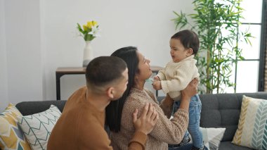 Çift ve oğul evdeki kanepede oturup birbirlerine sarılıyorlar.