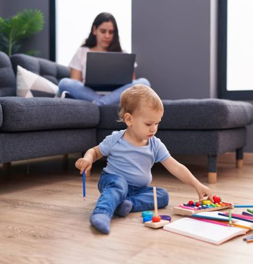Anne ve oğlu evde oynarken dizüstü bilgisayar kullanıyor.