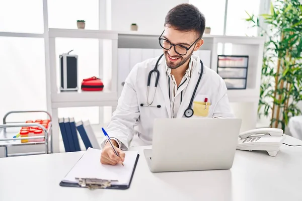 Young Hispanic Man Doctor Using Laptop Writing Medical Report Clinic — Stock Photo, Image
