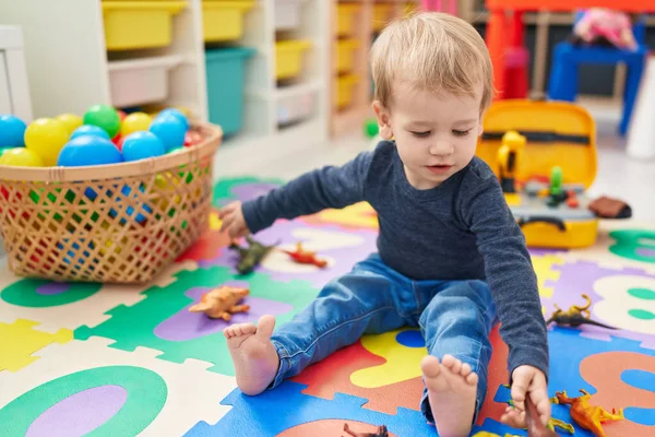 可爱的金发碧眼的幼儿在幼儿园的地板上玩恐龙玩具 — 图库照片