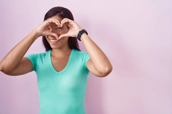 Jonge Spaanse Vrouw Staan Roze Achtergrond Doen Hartvorm Met Hand — Stockfoto