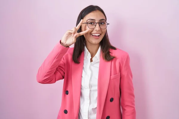 顔に指で平和のシンボルを行うビジネス服や眼鏡を身に着けている若いヒスパニック系の女性 勝利を示す陽気な笑顔 — ストック写真
